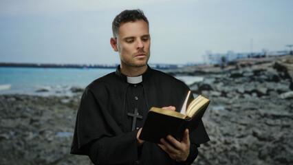 Clergyman reading at the rocky beach with an open book, capturing the serene seaside atmosphere.