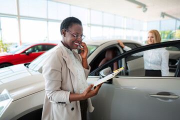 Car salesperson talking on phone in automobile showroom