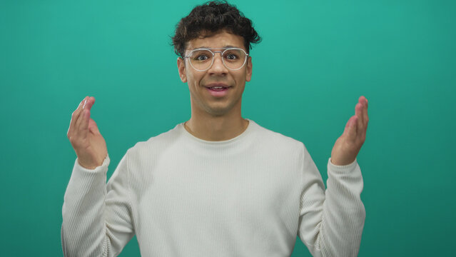 Man wearing glasses and a white shirt shrugs shoulders with puzzled expression in a teal studio set; uncertainty. - Powered by Adobe