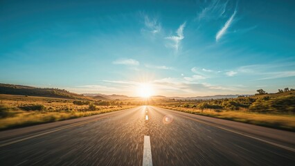 Naklejka premium Open road during sunrise with a clear sky, expansive landscape, and distant mountains.