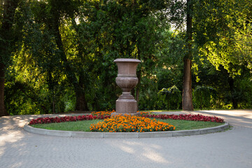 A large decorative stone garden vase placed in the center of a landscaped park in Chisinau, Moldova.