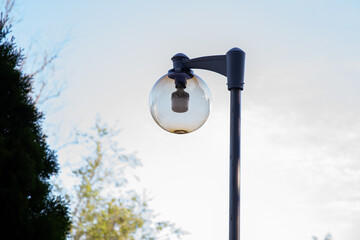 A round street lamp captured against a clear sky. The minimalistic composition emphasizes clean lines, soft daylight, and urban design elements