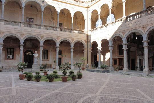 Historic Courtyard With Arched Gallery, Statues, and Sunlit Facade in Classic European Cloister - Powered by Adobe