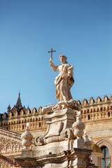 Statue Holding Cross Above Ornate Marble Base in Historic European Plaza