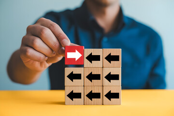 Man places a red block with a rightpointing arrow among blocks with leftpointing arrows symbolizing leadership strategy and standing out from the crowd on a yellow surface