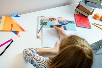 Teenage girl doing homework at table at home preparing for school test