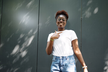 Young woman outdoors making expressive gestures and smiling, showing positive emotions and playful energy.