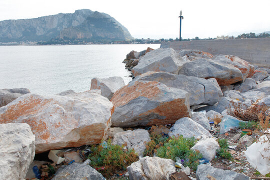 Rough Seaside Breakwater With Large Rocks and Litter Along the Coastline Near the Harbor - Powered by Adobe
