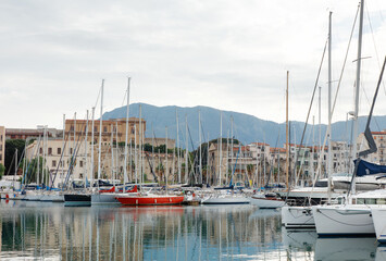 Marina With Sailboats And Town Docks Against Mountain Backdrop At Sunset
