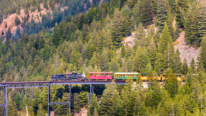 Historic tourist train crosses a bridge near I70 highway in Colorado