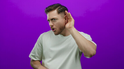 Young man with beard listening intently on a vivid purple background, highlighting focus and curiosity through expressive gestures and isolated environment.