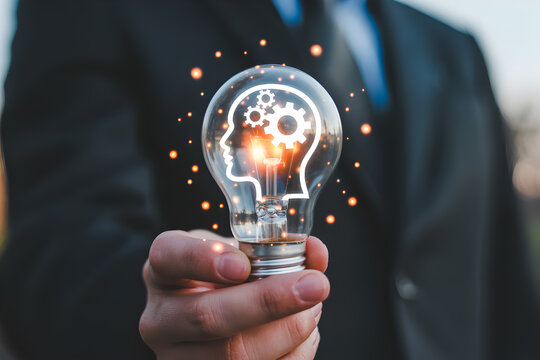 Man holds a lightbulb with a head and gears inside symbolizing innovation creativity and problemsolving in business technology and education representing new ideas and solutions - Powered by Adobe
