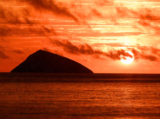 Fiery Sunset over a Distant Island Silhouette