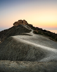 Path leading to a serene sunset view near ancient ruins in a rocky landscape