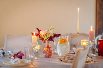 Elegant dining table setting with floral centerpiece, candles, and glassware, creating a warm atmosphere for special occasions and gatherings with friends and family