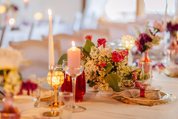 Elegant table setting adorned with vibrant flowers, candles, and decorative glassware, creating a romantic atmosphere for a special celebration or event