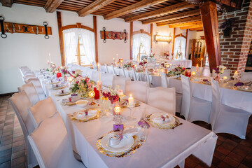 Elegant dining setup featuring beautifully arranged tables with floral centerpieces, candles, and fine china in a cozy venue, perfect for celebrations and gatherings