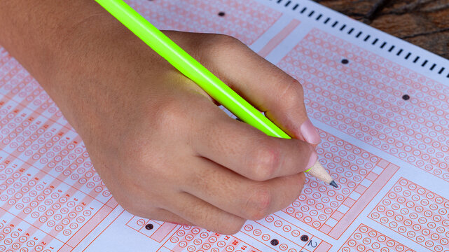 student hand with pencil exam paper