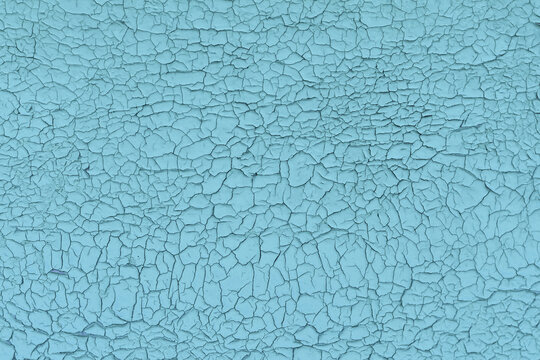 Old vintage cracked wall, blue pelling paint. Aged aquamarine flaky crackle surface.