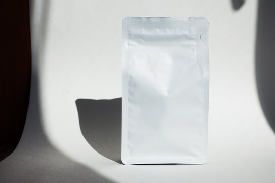 Blank craft plastic pouch, white pack on studio background with shadow, mylar bag isolated for coffee or food, cosmetic products, snack, candy. Different sizes, mock up.