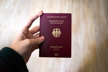deutscher Reisepass in einer weiblichen Hand vor einem hellen Hintergrund. die aufnahme zeigt klare details des burgunderroten Passes und vermittelt ein gefühl von Reisen