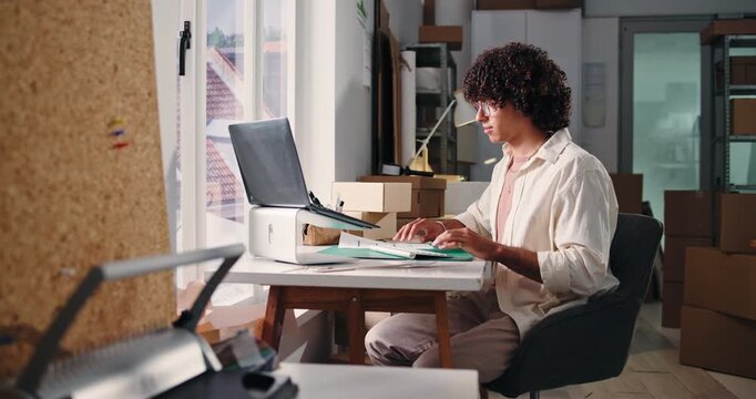 Man, laptop and reading document in startup for stock update, supply chain and shipping bills. Person, pc and paperwork with inventory checklist, quality assurance and order invoice for delivery cost