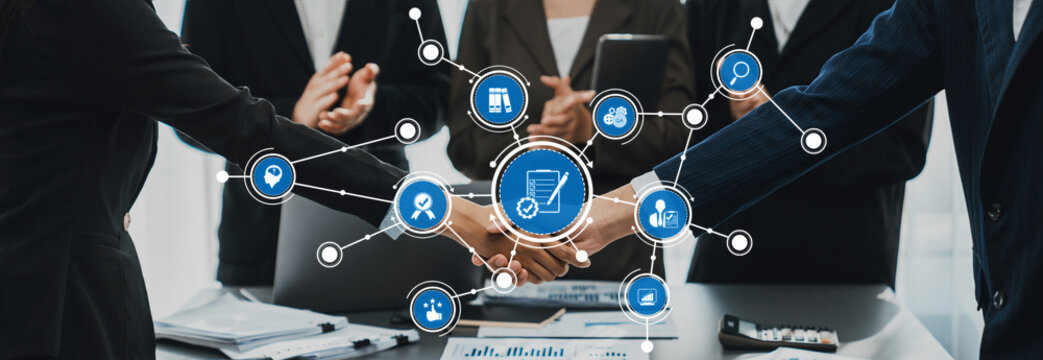 This image showcases a business collaboration theme featuring a handshake amidst a digital interface, emphasizing teamwork and professional relationships in a modern office environment. Amity
