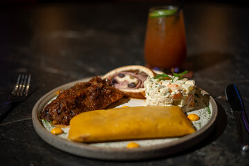 Venezuelan Christmas dish: hallaca, ham bread, chicken salad and pork leg, accompanied by a glass of iced tea with a slice of lemon.