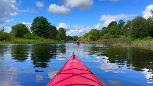 POV of kayaking on a red boat on the river in the forest