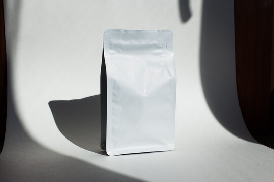 Blank craft plastic pouch, white pack on studio background with shadow, mylar bag isolated for coffee or food, cosmetic products, snack, candy. Different sizes, mock up.