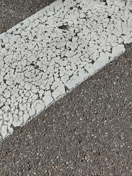 Primer plano de l&iacute;nea blanca de carretera desgastada y agrietada sobre textura de asfalto