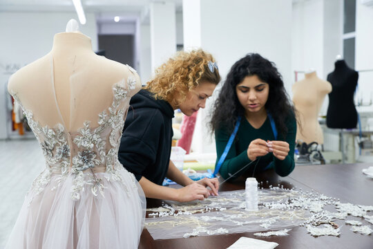 Mannequin with a wedding dress is in the tailor's shop. Dressmakers working in atelier. - Powered by Adobe