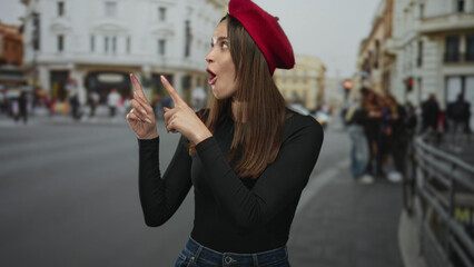 Fototapeta premium Woman points both index fingers upward on city street wearing red beret and black shirt; surprise curiosity.