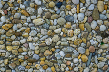 multicolored exposed aggregate texture closeup showing small round river stones embedded in grey cement concept of construction material, landscaping, exterior design