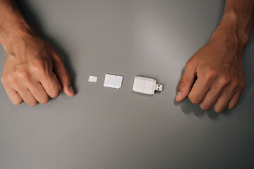 Top view of electronic technician comparing memory card sizes, from smallest to largest, including micro sd, sd card and usb drive, highlighting evolution of data storage technology, close-up.