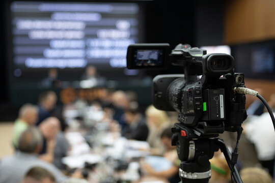 Camera during press conference with speaker in the background