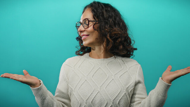 Woman with curly hair extending hands apart against blue background, showcasing a mature and friendly expression, ideal for concepts of comparison or decision making.