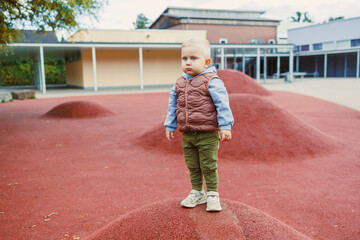 Child explores a vibrant playground, standing confidently on a hill of colorful material during a...