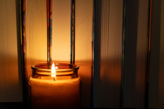 Candle Burning in Front of Books at Night