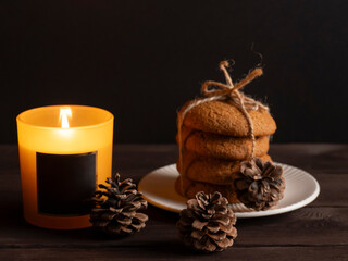Rustic Cookies and Burning Candle with Pinecones on Dark Wooden Table