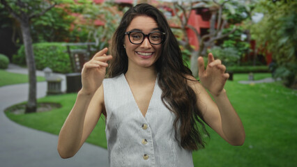 Woman with hands points thumbs to chest in forest; confidence.