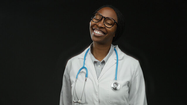 Woman doctor in white coat with stethoscope sending kiss on black background shines in professional setting with confidence and cheerfulness. - Powered by Adobe