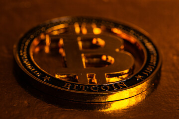 Extreme Macro of Physical Gold Bitcoin Coin on Warm Golden Surface