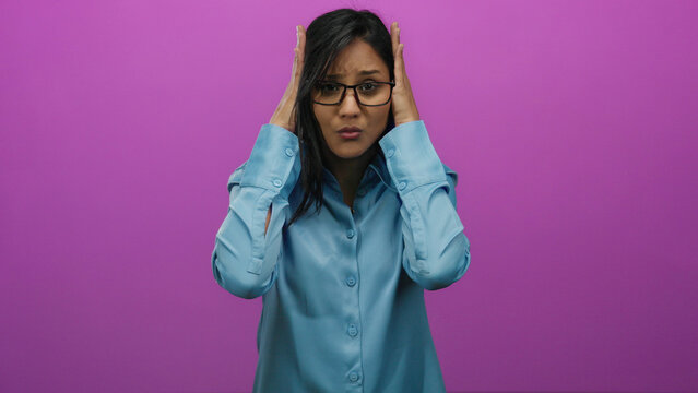 Young hispanic woman in stress holding her head in frustration against an isolated vibrant pink background, expressing overwhelmed emotions.
