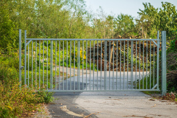 Closed metal gate blocking rural pathway.