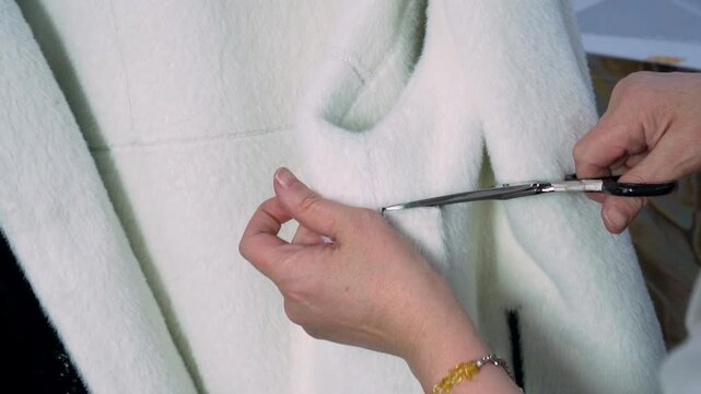 Leather jacket production worker cutting loose threads at a garment workshop