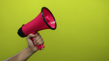 Man holding pink megaphone against bright yellow background implying communication, announcement, and expression emphasized by vibrant color contrast and simplicity.