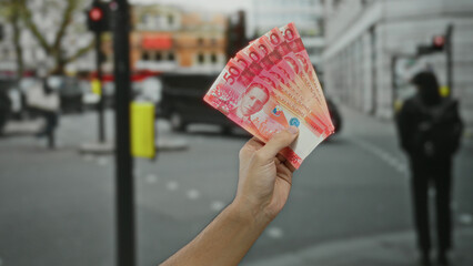 Man holding filipino pesos on a busy urban street, showcasing currency exchange or financial...