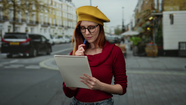 Woman in vibrant attire sketches outdoors on a city street, blending creativity and urban lifestyle with focus and elegance in an engaging cityscape backdrop.