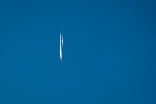 Plane trail and white clouds in the blue sky. Chemtrail conspiracy theory.